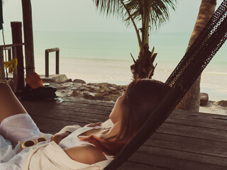 Beach relaxed vibe of Asian woman sleeping on hammock by the beach.