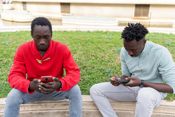 African men engaging with mobile phones outdoors, showcasing technology 