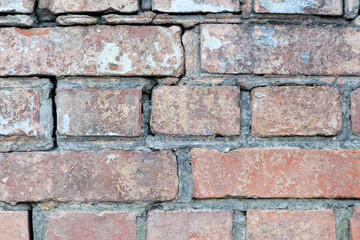 Obraz premium red old brick wall background, brick wall texture, structure. old broken brick, cement joints, close-up. crumbling from old age. macro photo. construction, repair. concept of devastation, decline