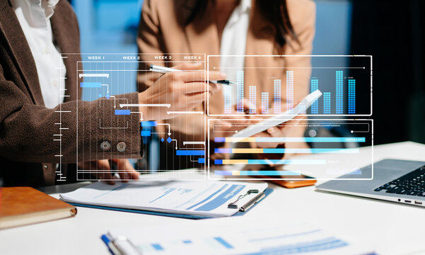 Businesswoman team Project manager working and update tasks and Gantt chart scheduling virtual diagram.with smart phone, tablet - Powered by Adobe