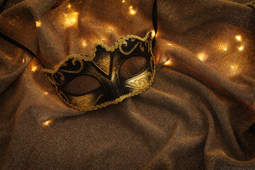 Venetian mask with gold decorations on a shiny background