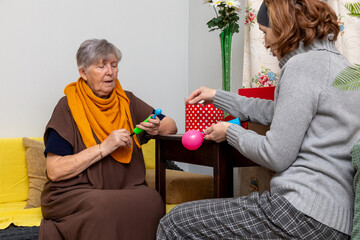Elderly woman and social worker preparing balloons. Seniors engage in fun activity. Home care, assistance, social support concept.