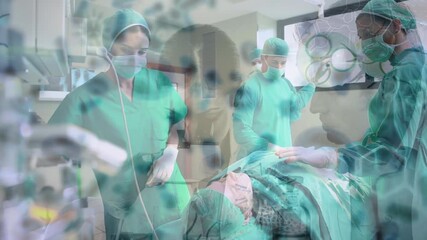 Animation of covid 19 cells over diverse surgeons wearing face masks in operating theatre - Powered by Adobe