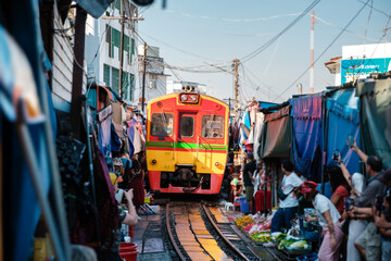 Colorful train crossing through the bustling Maeklong Railway Market in Thailands vibrant scene