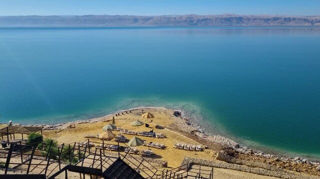 View over the Dead Sea, Jordan, showing a small beach, turquoise waters, and rugged shoreline, highlighting the shrinking coast and environmental impacts of climate change and agriculture