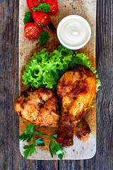 Roasted chicken drumsticks with mayonnaise on wooden table. Top view