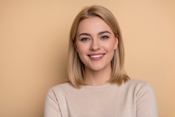 portrait of  smiling young blonde  woman on beige background 