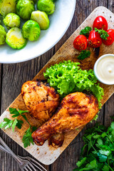 Roasted chicken drumsticks with mayonnaise on wooden table. Top view