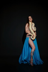 Woman performing dance with a snake in a dark studio setting at night