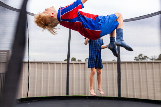 Aussie kids playing together after school bouncing on backyard trampoline at home