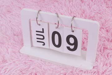 July 9 on calendar on pink carpet background