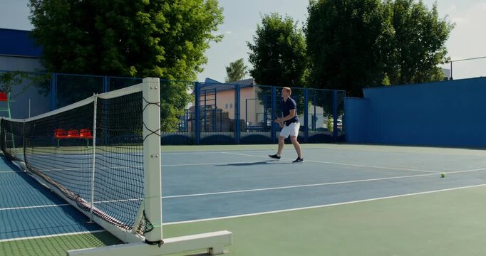 A guy moves around the court during a practice game.. Two male tennis players train on the court with rackets in hand.