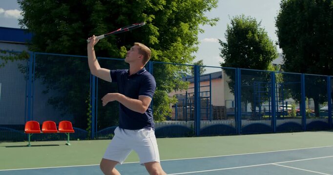 Close-up of a player hitting the ball with a tennis racket.. Two male tennis players train on the court with rackets in hand.