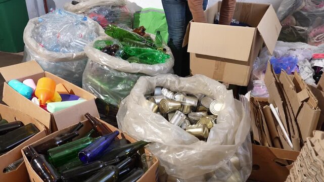 Recycling center with plastic, tin cans, cardboard boxes, textiles, shoes, old electronics and glass bottles, man sorting recyclable waste, sustainability, waste management