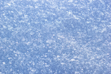 The closeup view of snowflakes and icy surface. The cold winter weather background with frosty crystals background.