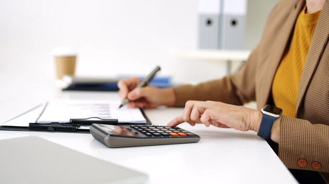 Close up of woman accountant using calculator to calculate tax refunds or  finance. woman doing finance with calculate expenses with laptop computer on office table.