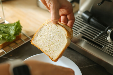 Hand holding slice of white bread by toaster in kitchen setting