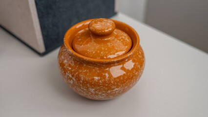 Rustic orange ceramic container with lid on white surface