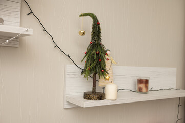 Fototapeta premium Decorative shelf with miniature christmas tree and candles in cozy interior