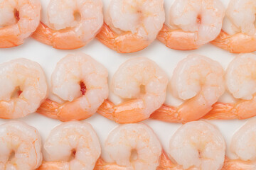 Peeled white shrimp with tails-on, arranged in a rows