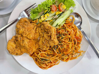 Crispy fried chicken served with spaghetti pasta and vegetables, hearty comfort food meal