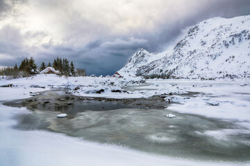 Amazing winter scenery with snowy  mountain peaks  on the shore of Rolvsfjord on Vestvagoy island at Lofotens.