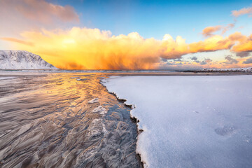 Astonishing winter scenery on Skagsanden beach with illuminated clouds during sunrise.