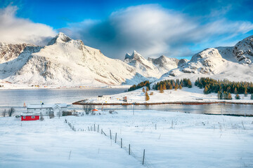 Amazing  winter view on Selfjorden with small fishing houses (rorbu) and snowy peaks on background.