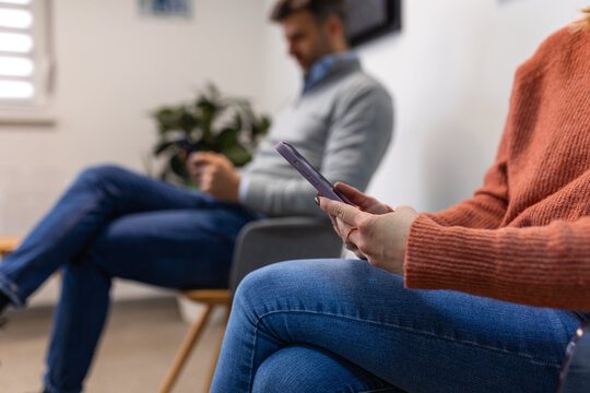 People, man and woman sitting in a queue, and waiting for a doctor's appointment in the hospital. Waiting room concept.