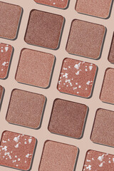 Fototapeta premium Eyeshadow palette background, mix of matte and shimmer shades brown, beige hues. Aesthetic top view pattern for beauty, makeup, cosmetics themes, Neutral colored swatches eyeshade refills