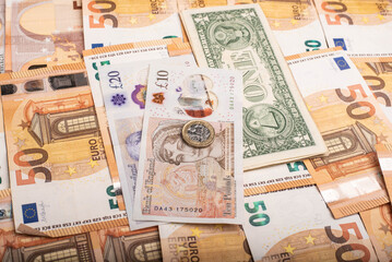 Close-up of international banknotes and coins: Pound, Euro, and Dollar.