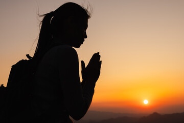 A silhouette of a woman praying at sunset, perfect for inspirational or faith related themes. spiritual religious background, prayer, meditation concepts.