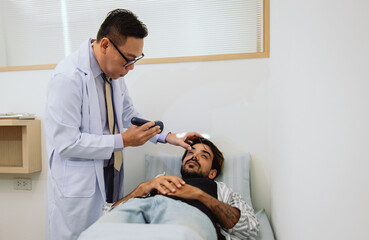 man is laying on  hospital bed while  doctor examines his head