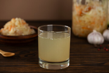 Fresh homemade sauerkraut juice or brine with sauerkraut salad in a plate and jar on a brown wooden table. Probiotic food.