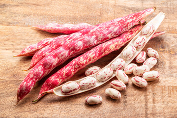 Borlotti bean or cranberry bean pods and open bean pod close up on wooden background.