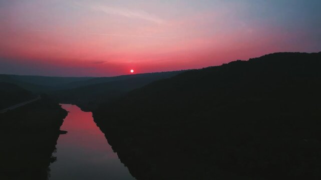 slow backward motion capturing an evening reddish tones reflecting on a small river. dark,calm atmosphere with natural reflection and peaceful mood