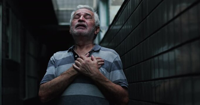 Elderly man holding hands to chest in narrow corridor, seeking God presence, divine grace, faith during hardship, surrender, spiritual vulnerability