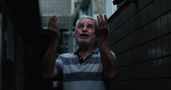 Elderly man raising hands toward sky in narrow corridor, tearful faith, fear and hope, asking God for help, divine intervention during difficult times