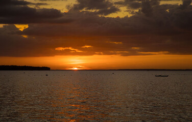 Naklejka premium Sunset over the sea on the horizon next to a tropical island