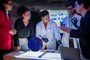 engineering research group analyzing a silicon wafer prototype. Professors and students collaborating on a microchip physics experiment in laboratory to develop future electronic technology.