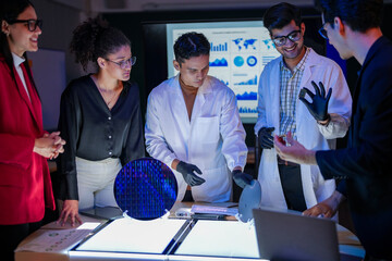 engineering research group analyzing a silicon wafer prototype. Professors and students collaborating on a microchip physics experiment in laboratory to develop future electronic technology.