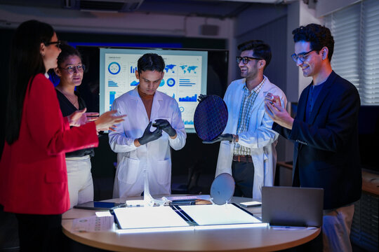 scientists and executives collaborating on Artificial Intelligence AI hardware development. Specialists inspecting a silicon wafer and high-speed RAM memory chip in a semiconductor laboratory. - Powered by Adobe