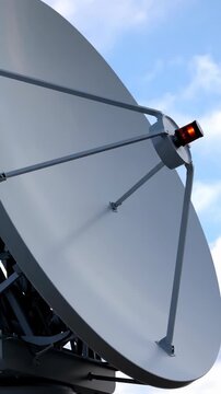 A large satellite dish points skyward, displaying "receive" on its feed horn. This technology captures signals from space, enabling global communication.