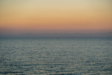 Obraz premium Calm sea horizon at sunset with soft pastel sky and gentle ocean waves