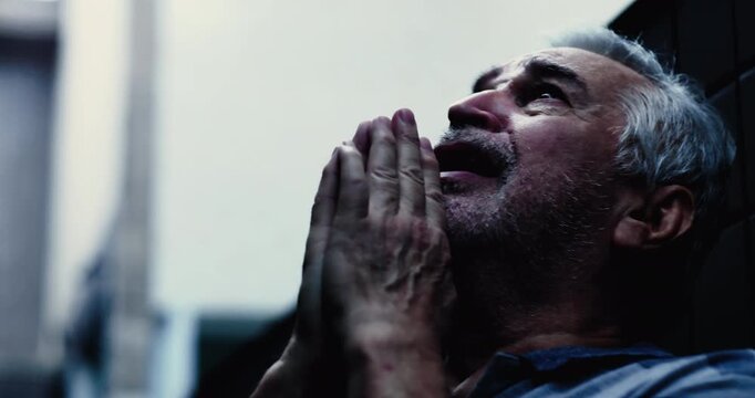 Senior man looking upward with hands clasped in prayer, seeking God help, desperation and faith, pleading for divine intervention during difficult times