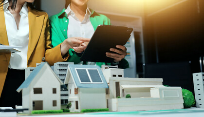 
 Two business people team planning and discussing of sustainable and renewable clean energy product with solar cell and wind turbine generator, CO2 emissions climate change global warming project