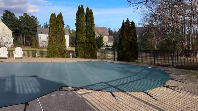 Wide view, residential scene of seasonal swimming pool protection with winterized cover