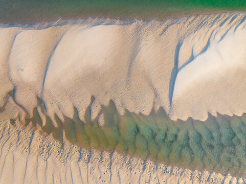 Aerial view of abstract pattern and water flow over sand in a coastal lake system