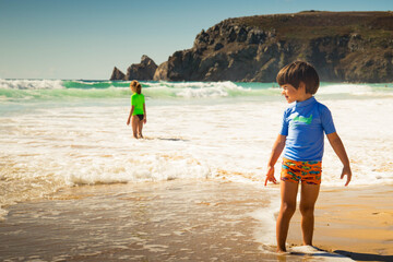 Two children, boy and girl, with green and blue t-shirt, standing in Pen Hat beach on the atlantic coast in Camaret-sur-Mer. Finistere, Brittany, France. Profile portrait.