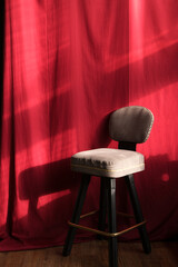 Elegant gray upholstered bar stool positioned against a rich red backdrop, showcasing soft textures...